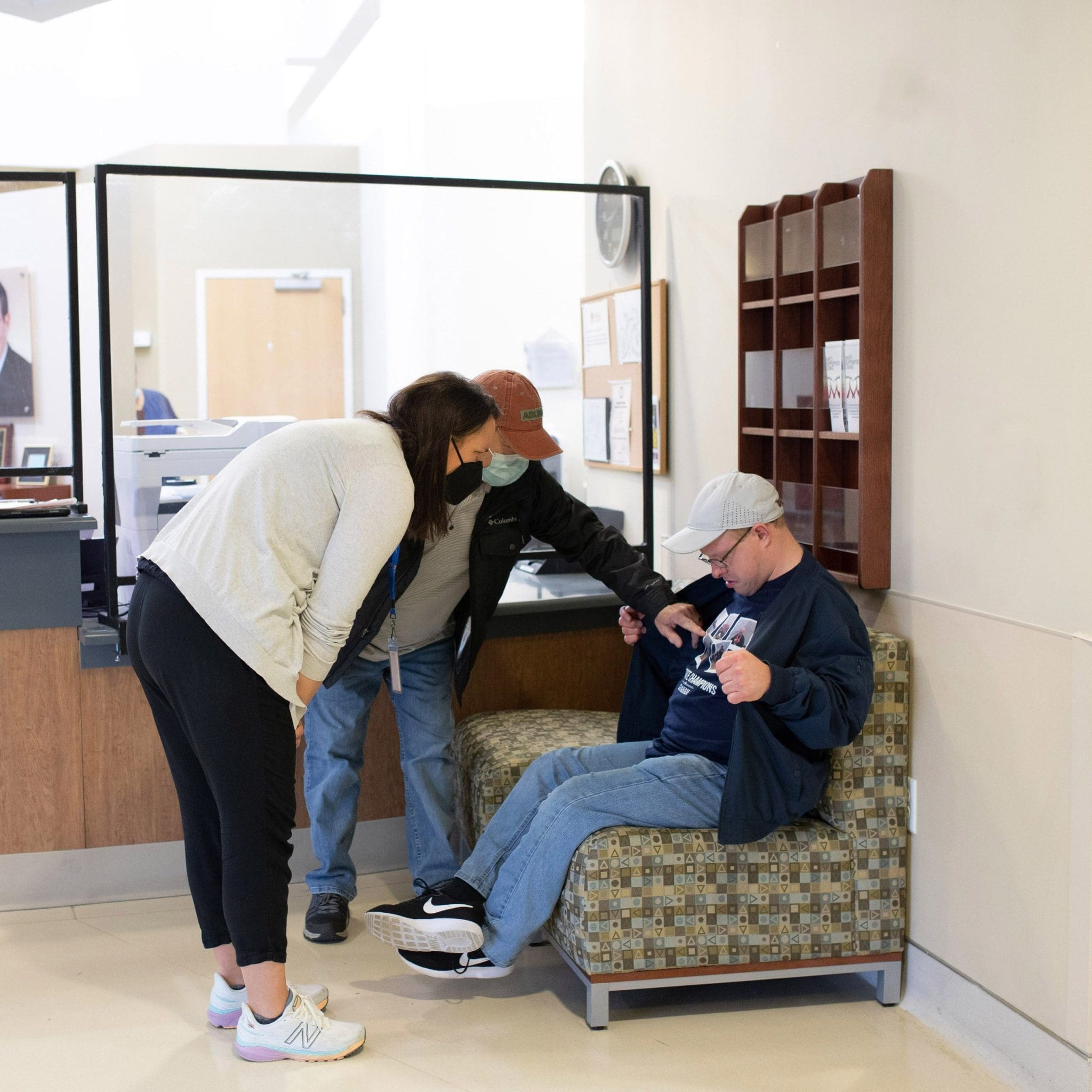 Young man with intellectual and developmental disabilities (IDD) proudly shows off his t-shirt to caregivers, fostering confidence and self-expression in a supportive healthcare environment.