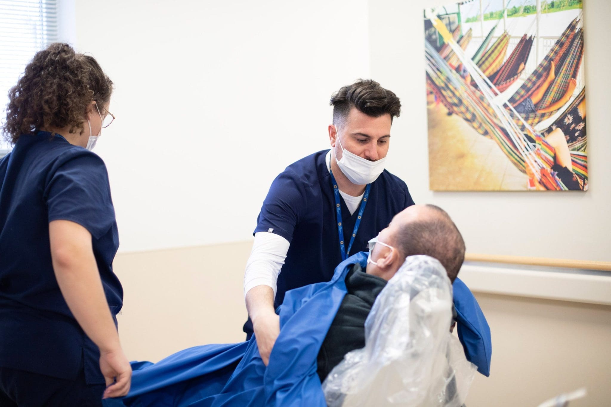 Behavior Analyst collaborates with a nurse to create a sensory-friendly experience for a man with an Intellectual and Developmental Disability using a weighted blanket.