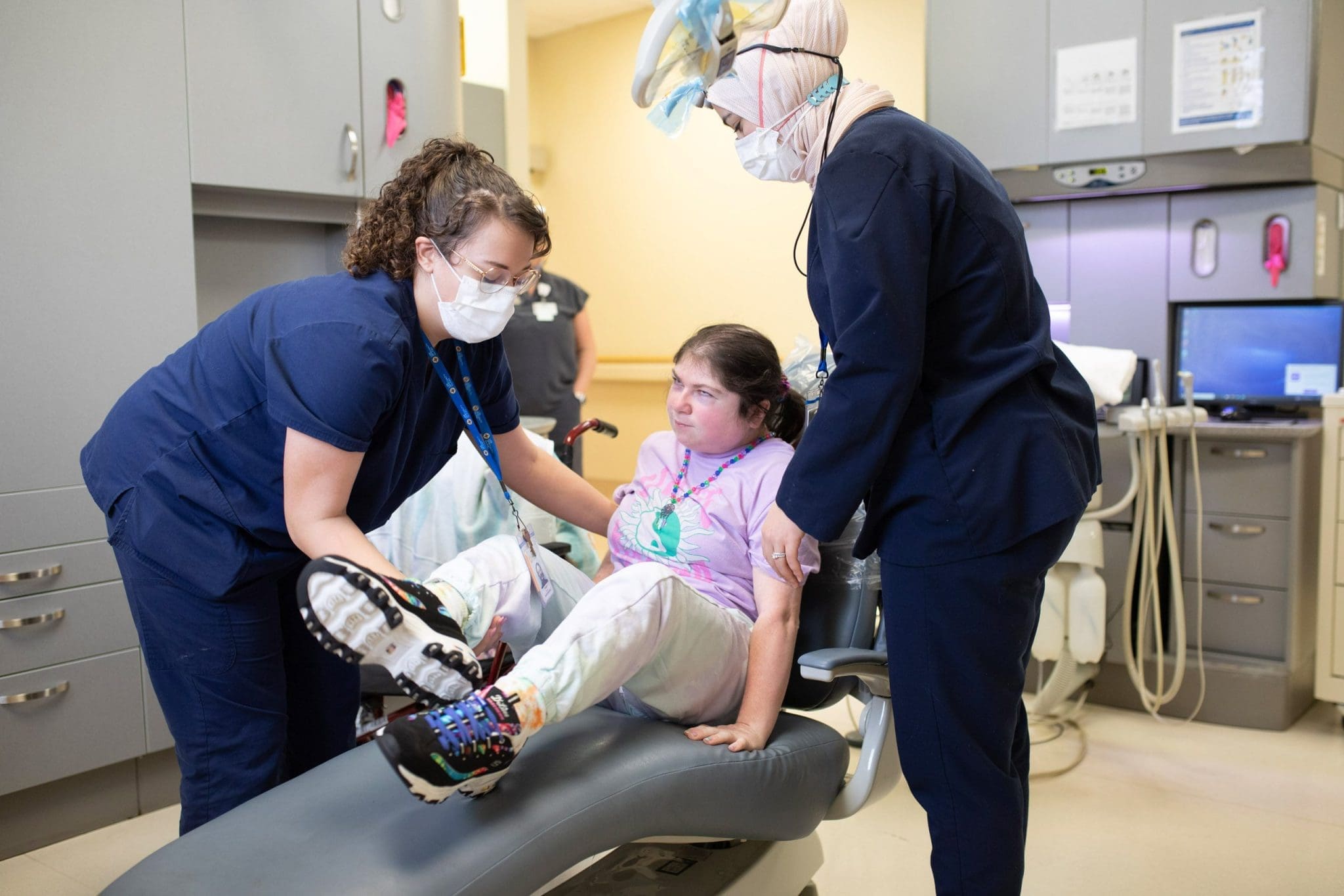 Two dentists provide sensory-friendly dental care to a young woman with intellectual and developmental disabilities (IDD), ensuring a comfortable and stress-free experience.