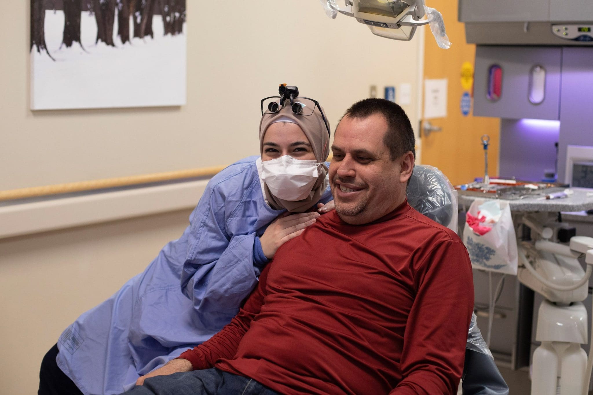 Dental provider wearing mask and headlamp with a patient in a dental treatment room