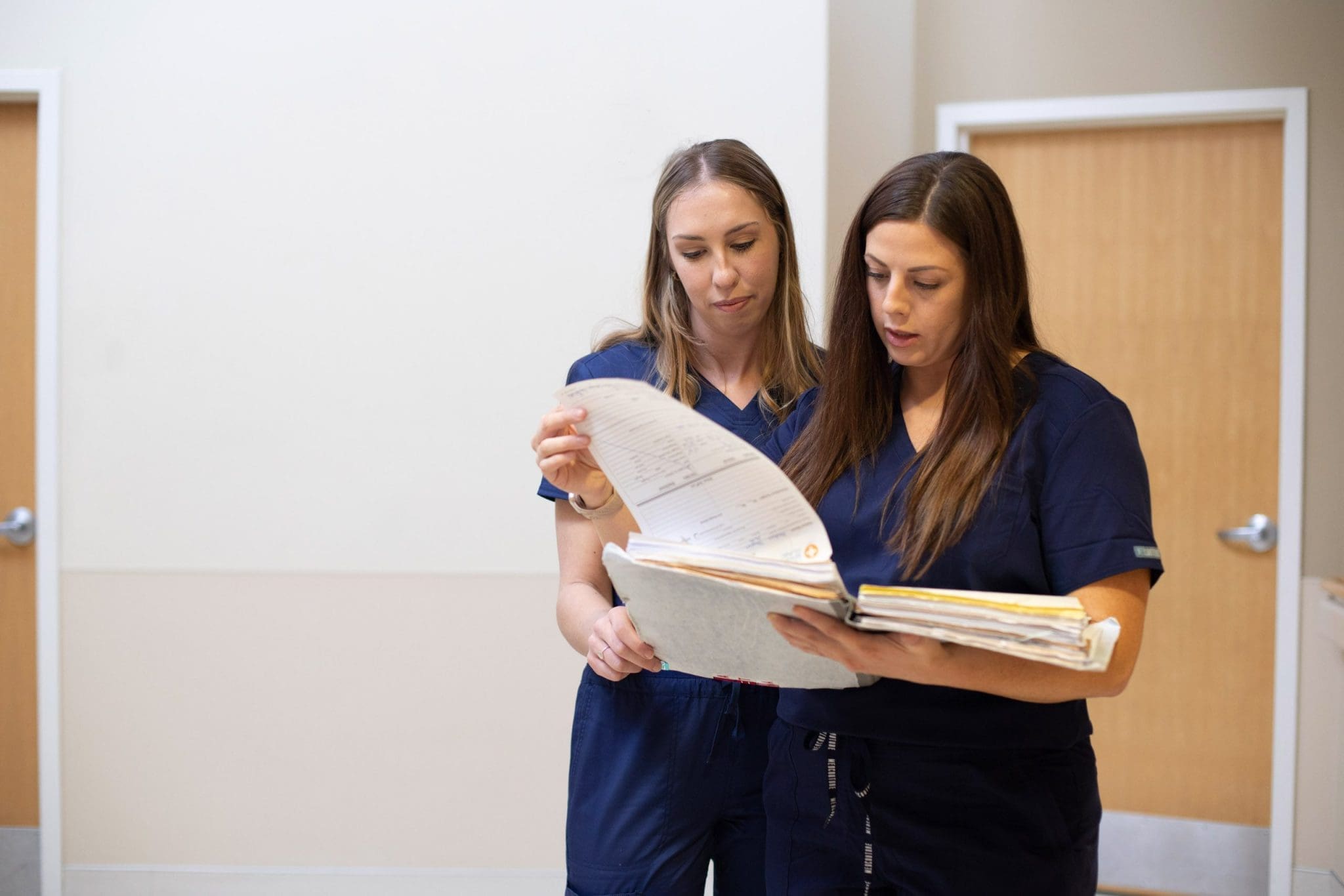 Two healthcare staff members review patient paperwork, ensuring coordinated and comprehensive care for individuals with intellectual and developmental disabilities (IDD).