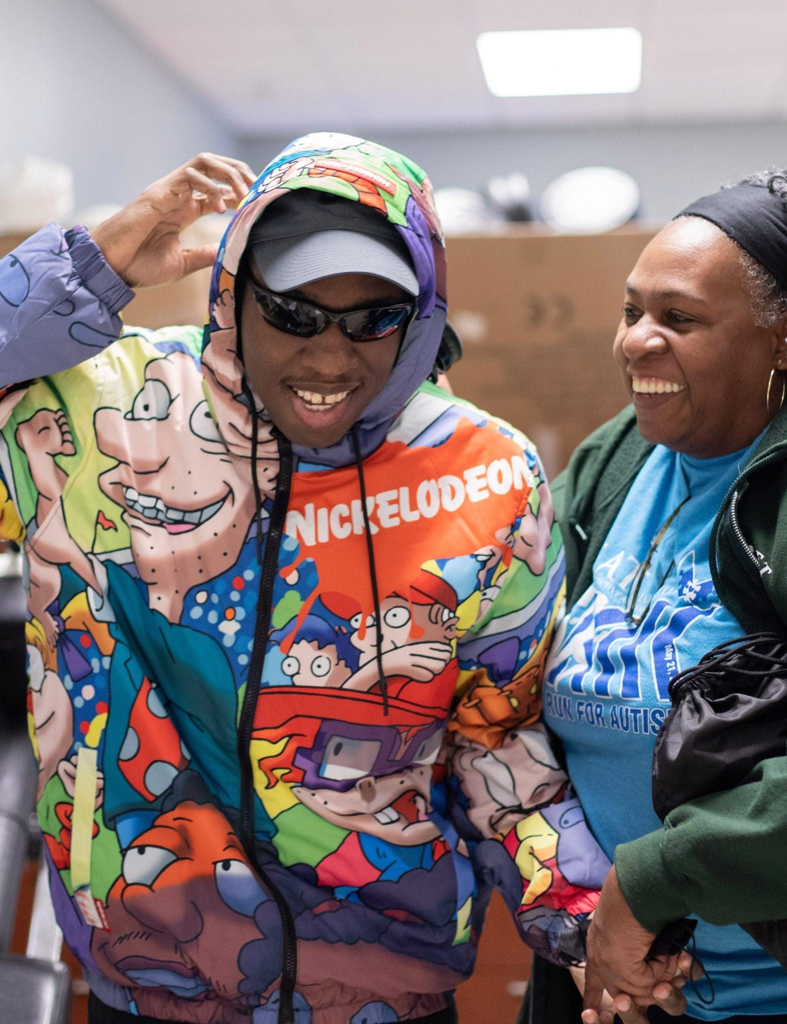 Young man in a brightly colored jacket grins as he walks alongside his smiling mother after multiple appointments, feeling accomplished and supported.