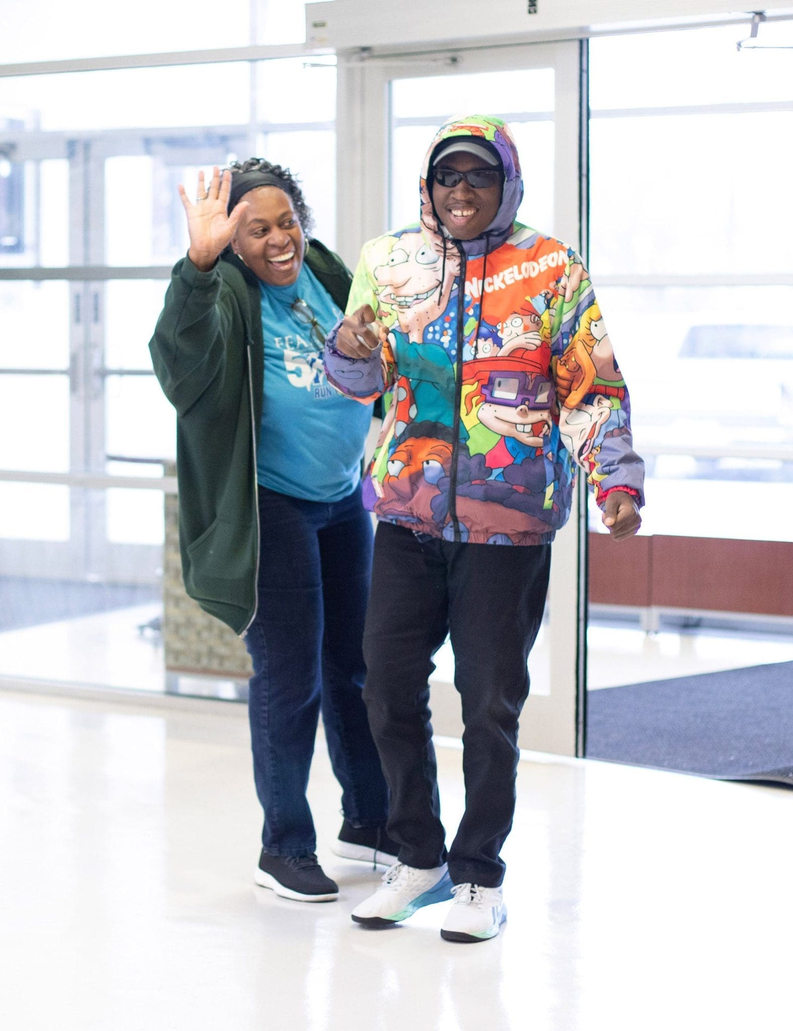 Smiling mother and her son with Intellectual and Developmental Disabilities (IDD) wave goodbye after a comprehensive healthcare visit at specialized clinic.