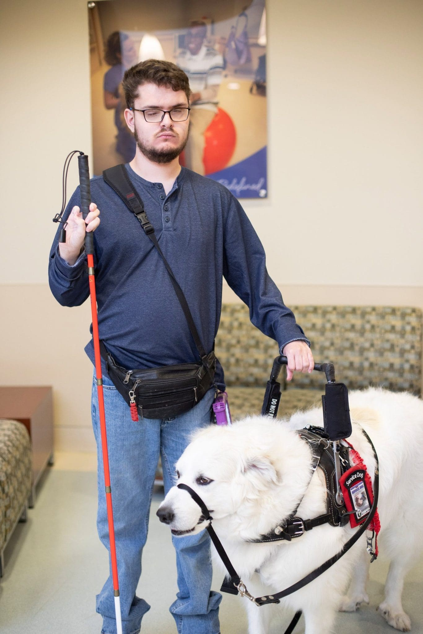 Young man with Intellectual and Developmental Disabilities (IDD) and visual impairment stands with his service dog at sensory-friendly healthcare clinic ready to receive patient-centered care.