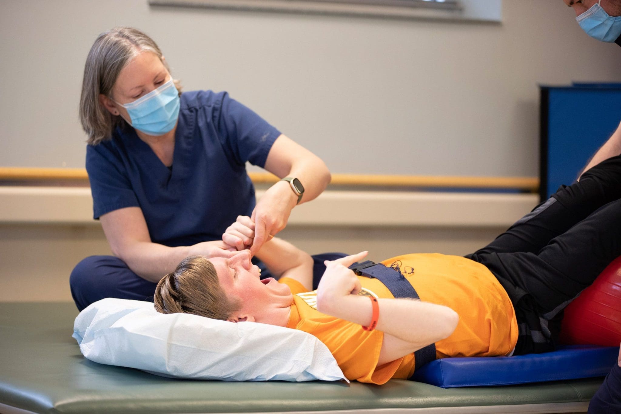 Therapist assists a patient with cerebral palsy in guided stretching exercises to improve mobility, flexibility, and muscle strength.