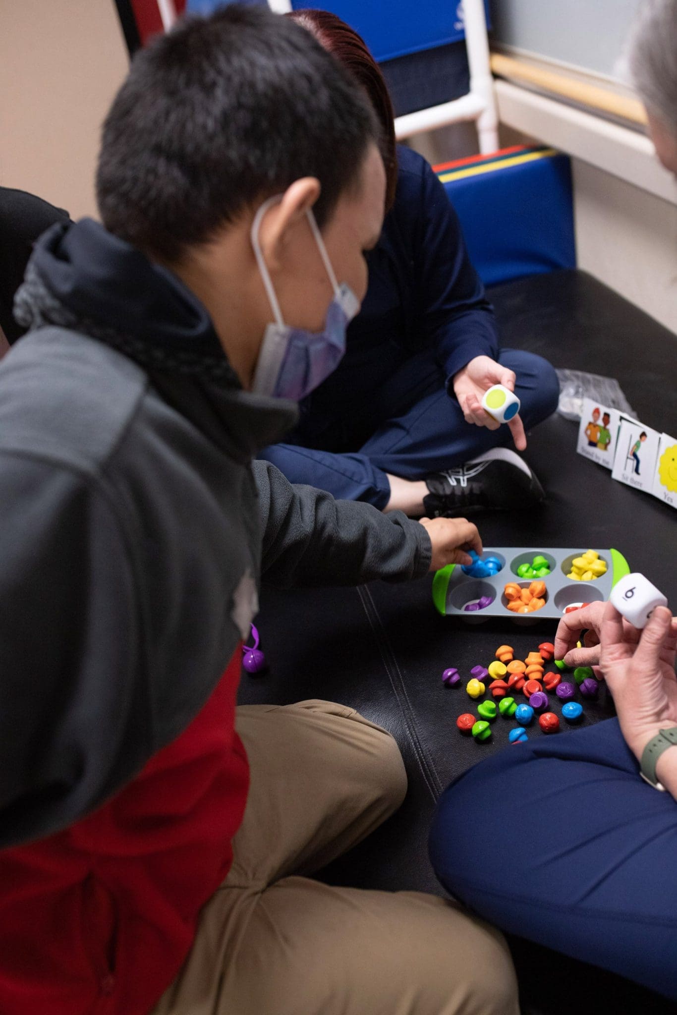 Man with Autism Spectrum Disorder (ASD) sorts colored objects as part of occupational therapy, enhancing fine motor skills, cognitive development, and sensory integration.