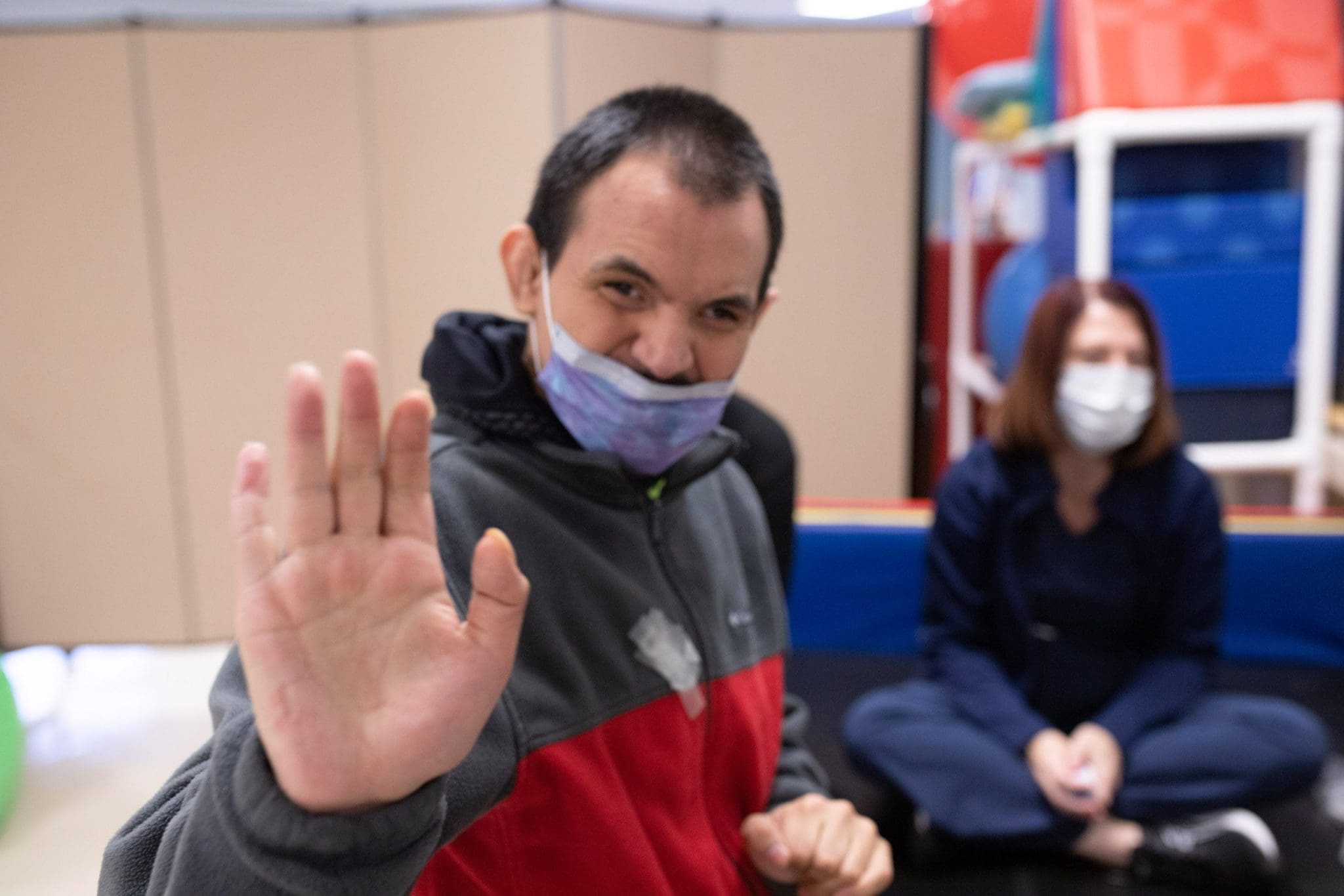 Man with Intellectual and Developmental Disabilities (IDD) waves happily during his sensory-friendly medical appointment