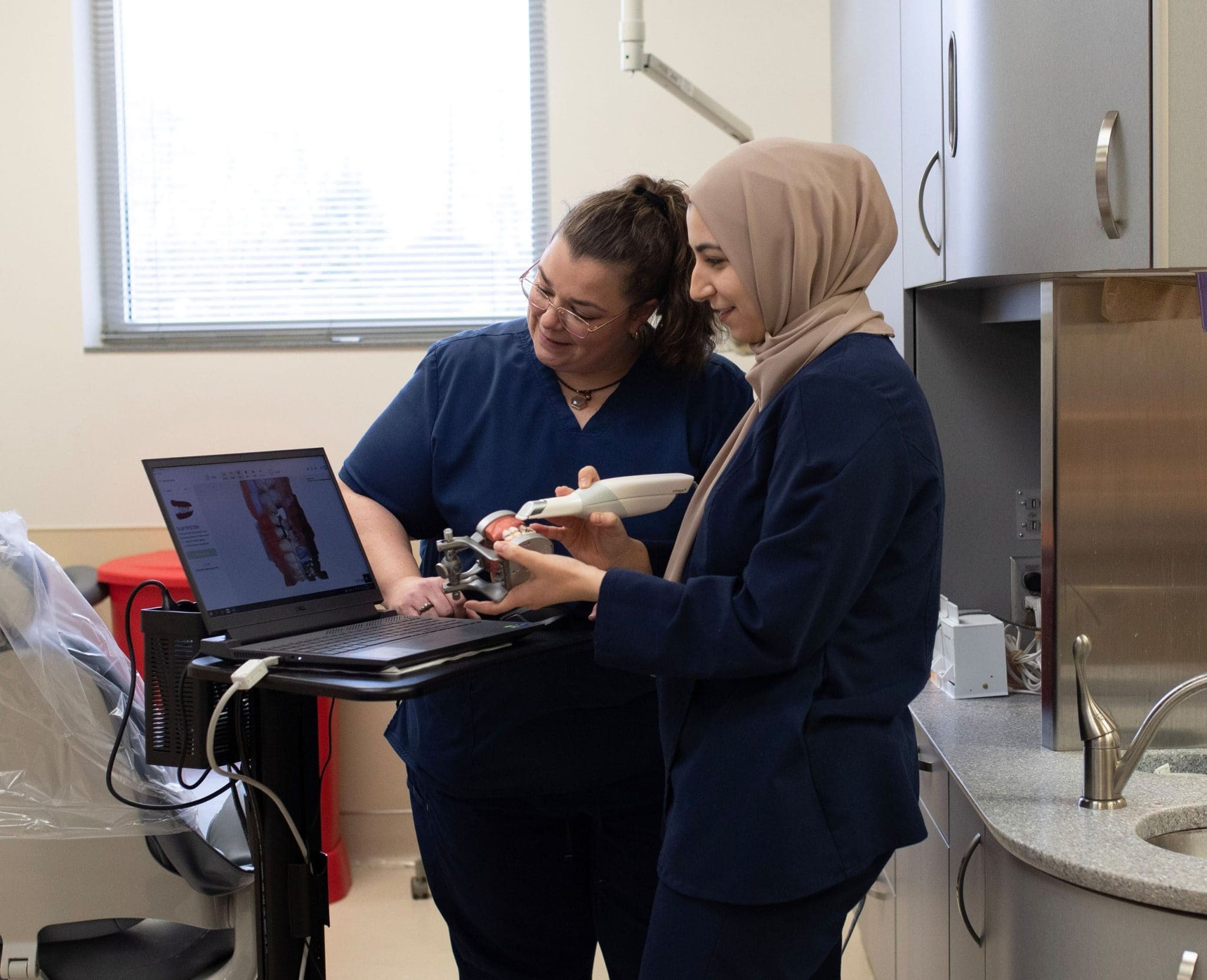 A skilled dentist wearing a hijab teaches a student dentist proper examination techniques during a hands-on training session in the Lee Specialty dental clinic for individuals with intellectual and developmental disabilities (IDD)