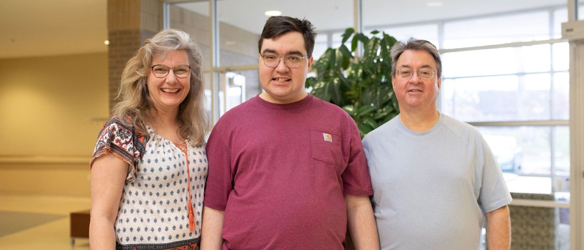 A happy family—father, mother, and their autistic son—smiles for the camera, grateful for the compassionate, specialized healthcare their son receives.