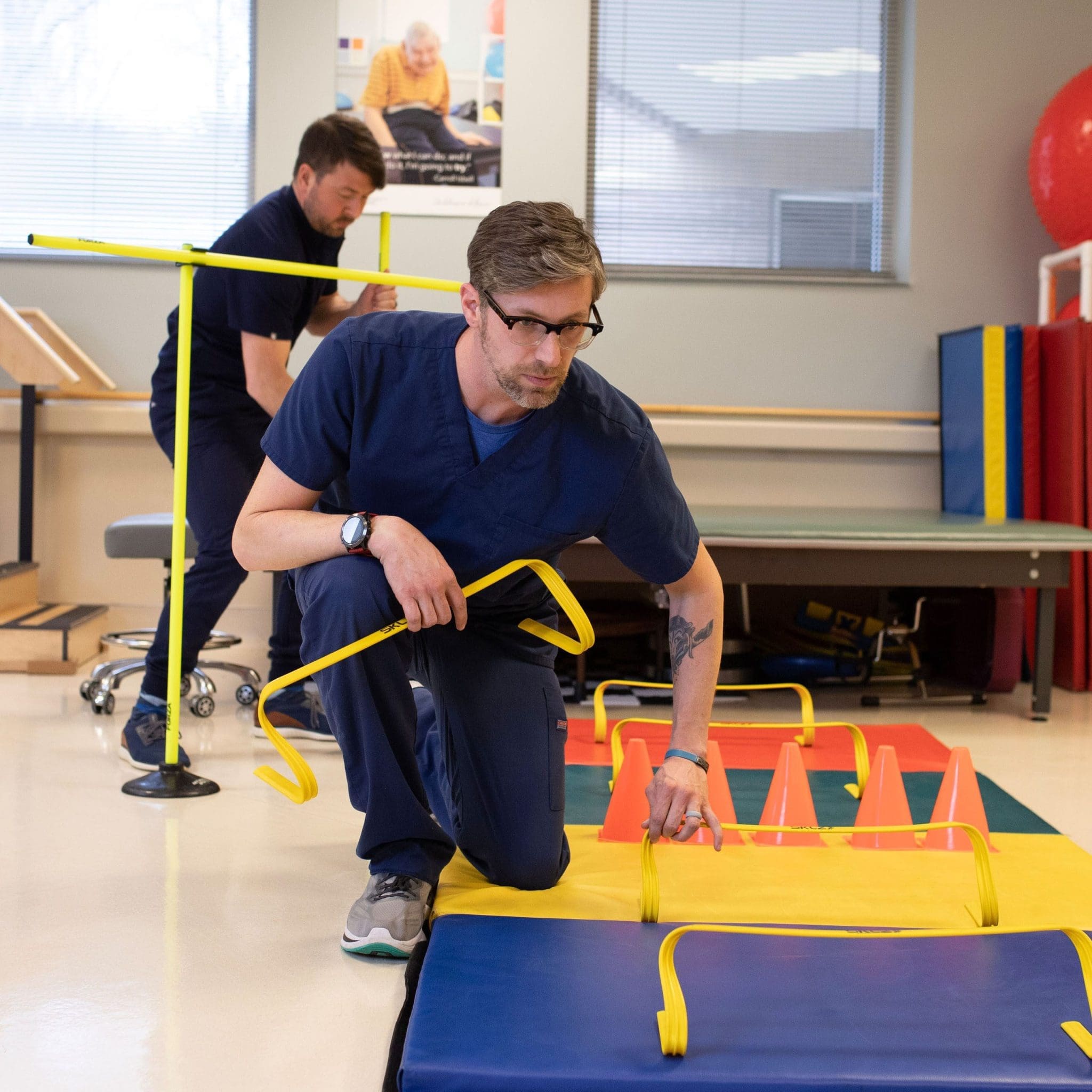 Two Occupational therapists setting up a sensory-friendly obstacle course for a patient with intellectual and developmental disabilities (IDD) to improve mobility, coordination, and daily living skills.