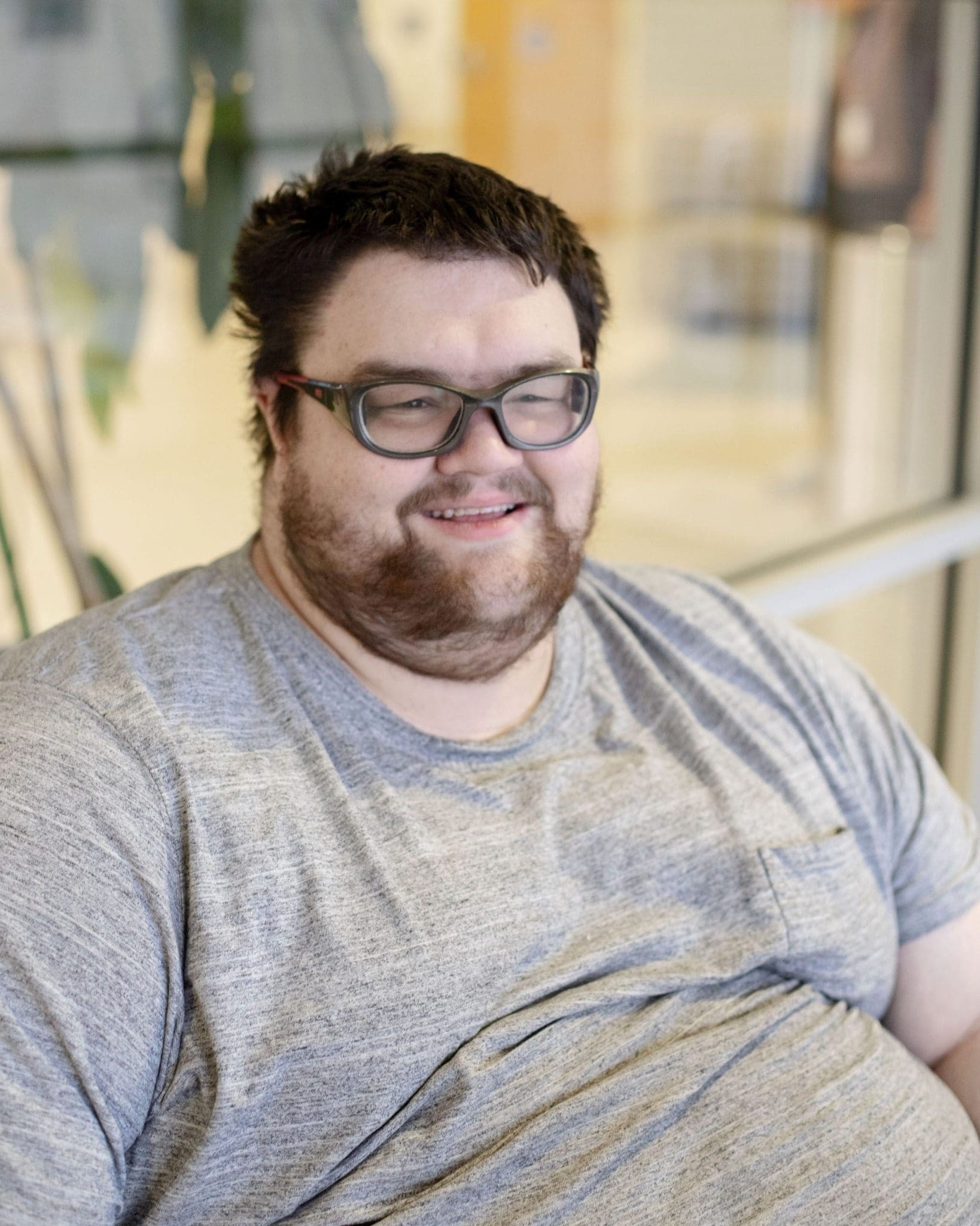 A young man on the autism spectrum smiles during a doctor's appointment, feeling comfortable and at ease.