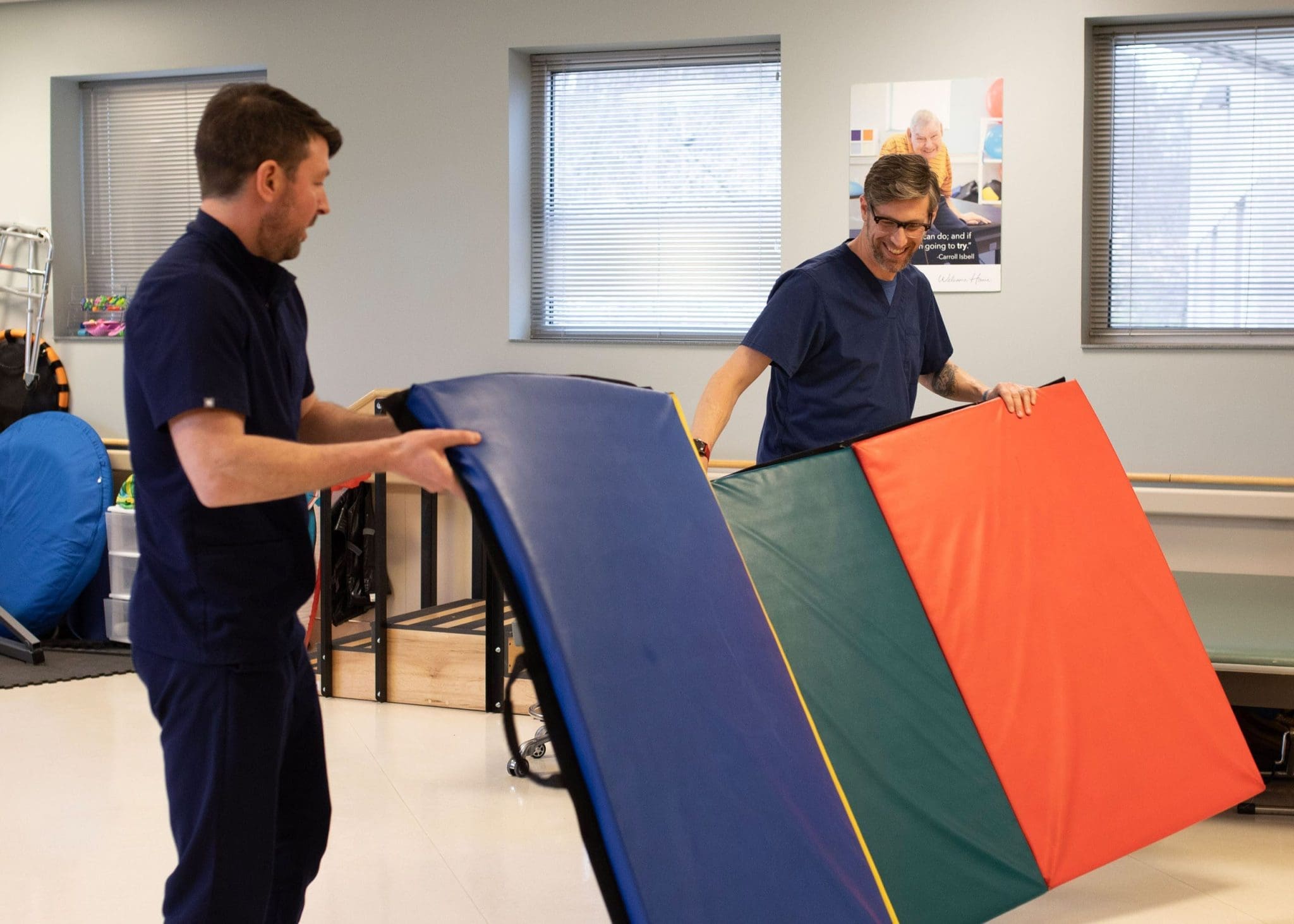 Two therapists set up a dynamic obstacle course to support mobility, coordination, and balance training for patients with intellectual and developmental disabilities (IDD) in a physical rehabilitation session.