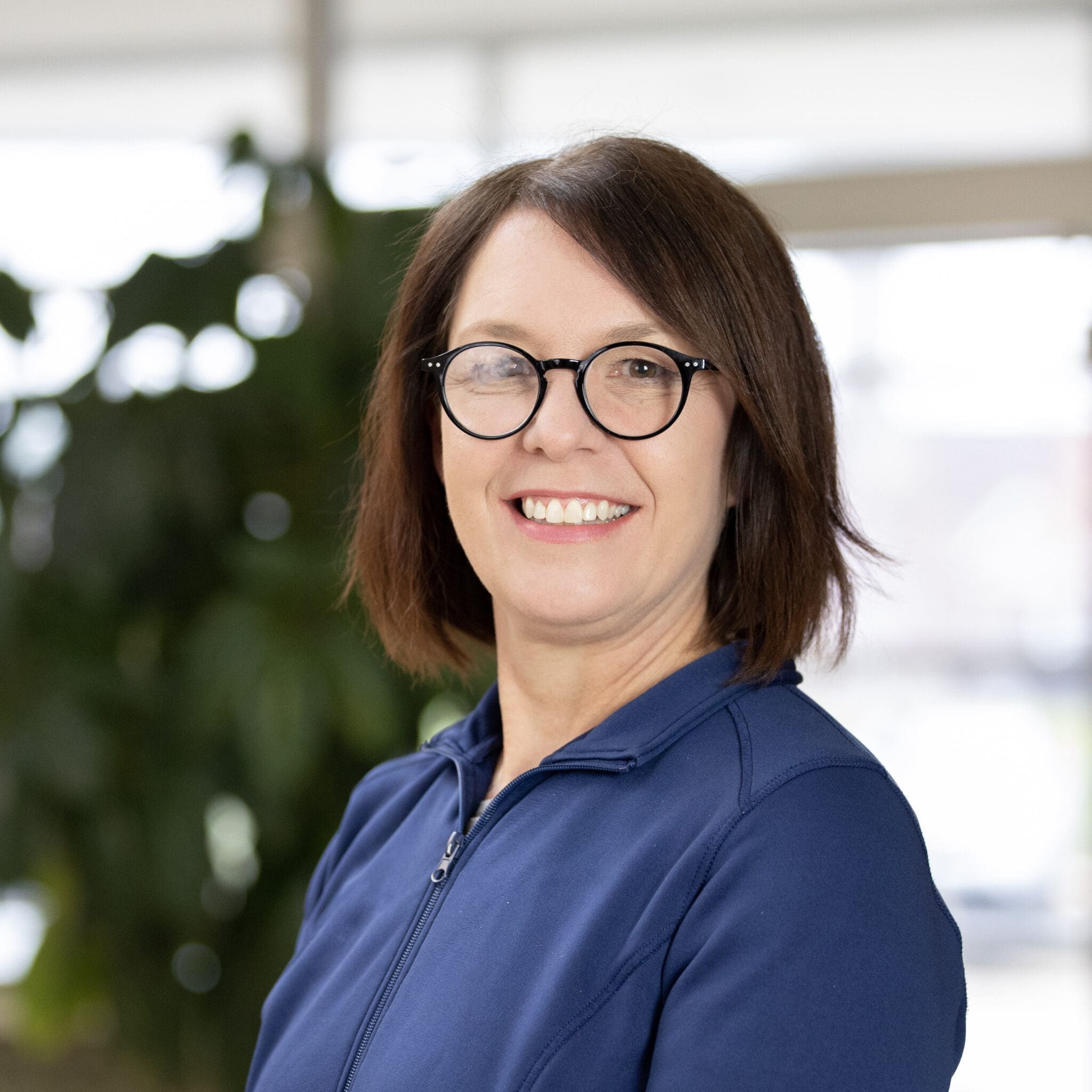 Lee Specialty Clinic staff member smiling with glasses and blue jacket