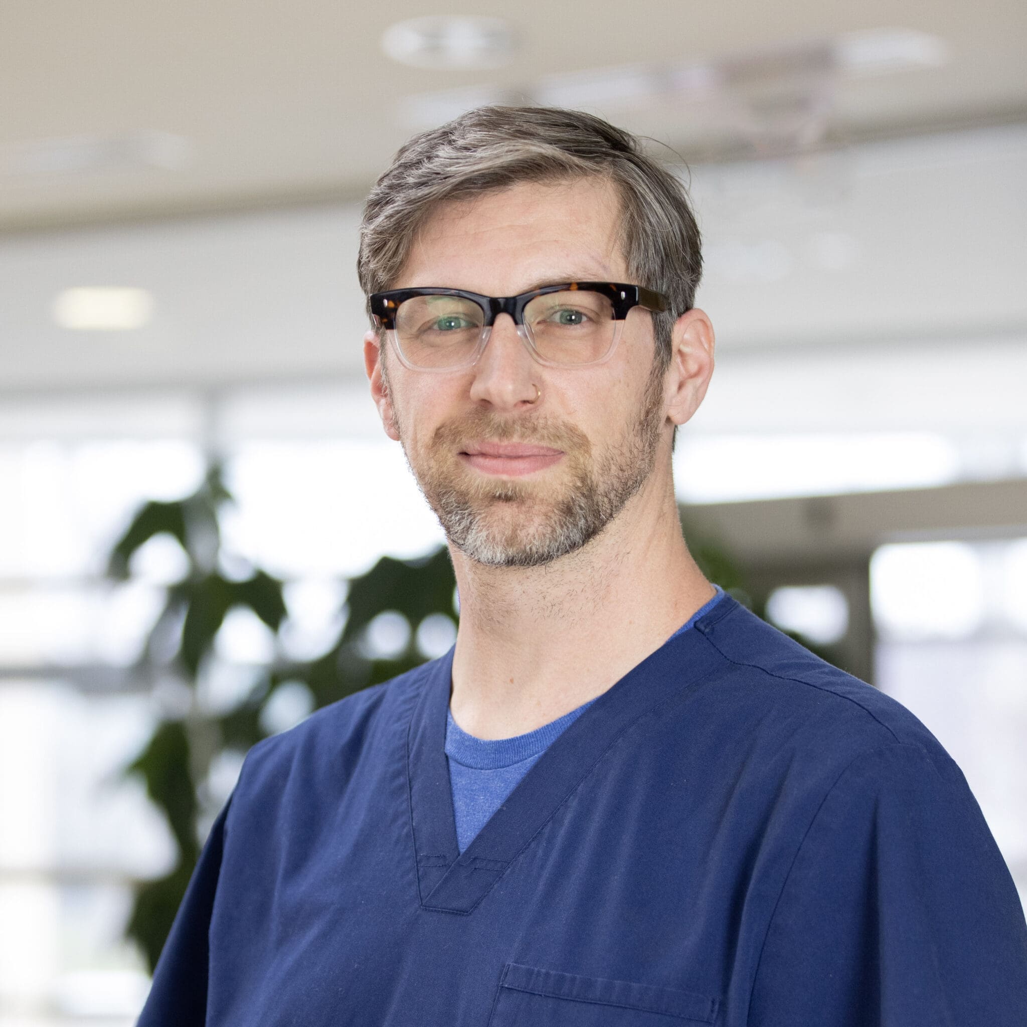 Lee Specialty Clinic staff member wearing glasses and blue scrubs