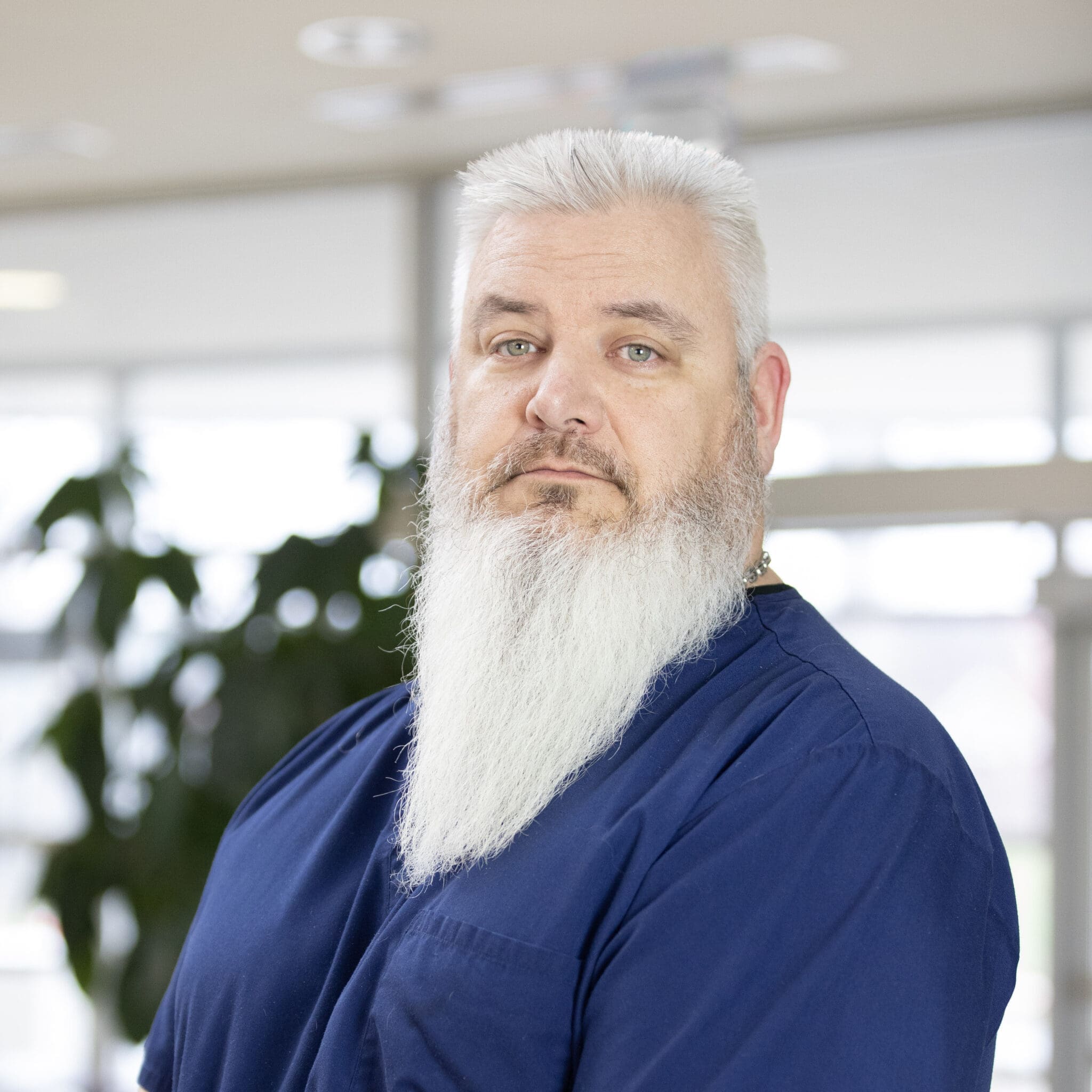 Lee Specialty Clinic staff member with long white beard wearing navy scrubs