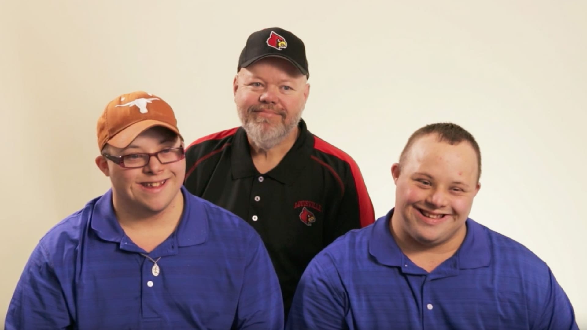 Three people smiling against a plain background